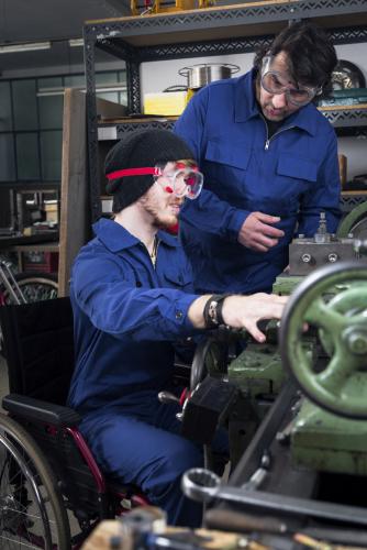 Mechanic working with apprentice in wheelchair at job site